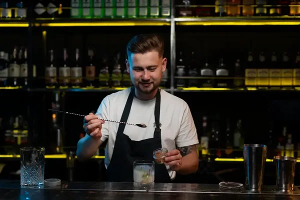 Crafting cocktails, a skilled bartender enhances the inviting atmosphere of a cozy bar.