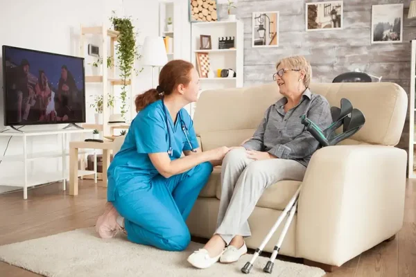Compassionate caregiver and elderly woman share a warm moment in a cozy living room.