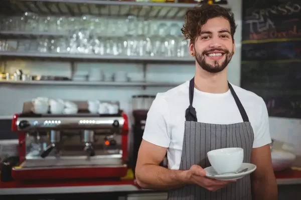 Cheerful barista in a stylish café, ready to serve quality coffee with a smile.