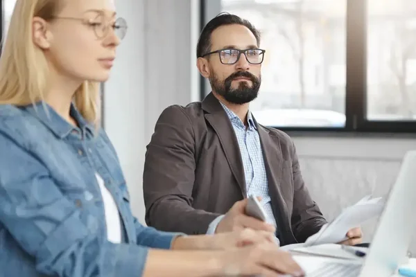 Professionals collaborate in a bright office, blending casual and formal styles for productivity.