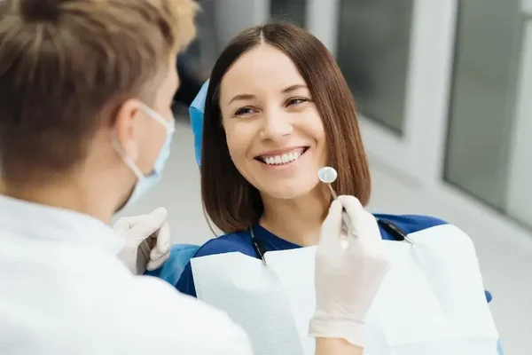 Cheerful young woman enjoys a friendly dental checkup in a bright, welcoming clinic.