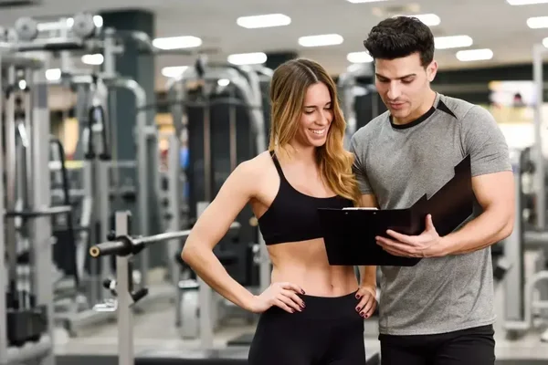 Fitness mentorship thrives as enthusiasts share insights in a vibrant gym setting.