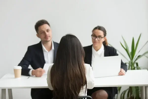 Focused candidate undergoes a job interview with attentive interviewers in a bright, modern office.