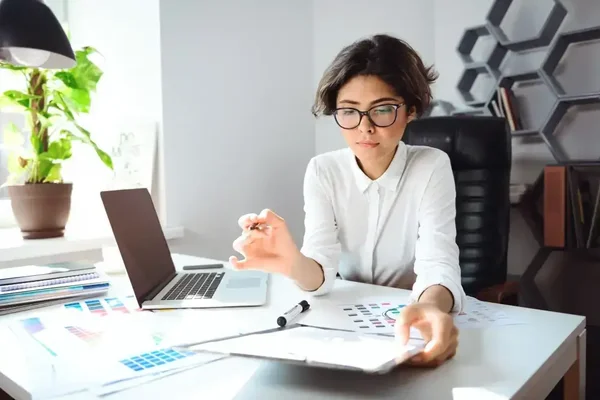 Young woman analyzing data in a bright, stylish modern workspace with creative elements.