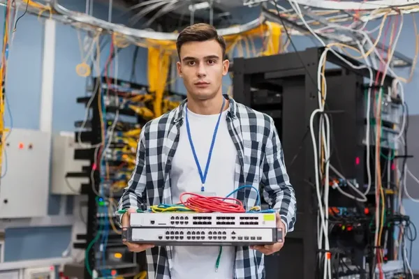 Young technician focused on managing network switch in a chaotic data center environment.