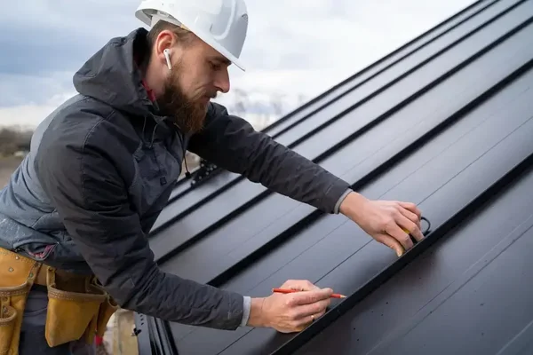 Skilled roofer measuring precisely on a metallic roof under overcast skies for quality installation.