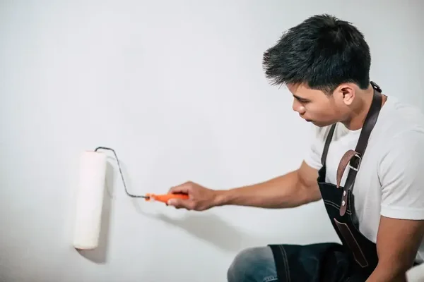 Dedicated young man painting a white wall, showcasing DIY home improvement and creativity.