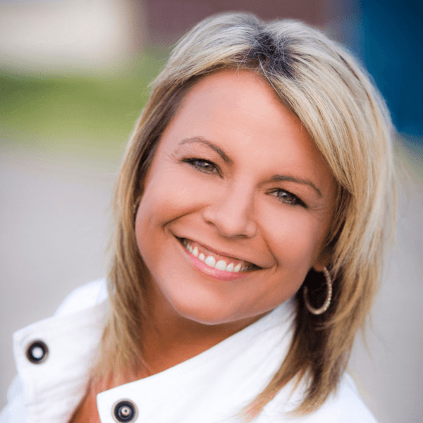 Shannon Barnum, a REALTOR® with Modern Market REALTORS®, smiling outdoors with blonde hair, wearing a white jacket and silver hoop earrings.