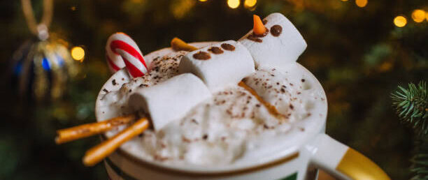 12-irresistible-christmas-ice-cream-recipes-for-your-holiday-table-image-5-hot-chocolate-sundae-with-a-marshmallow-snowman-topping-it-with-festive-decor-in-the-background-frosted-fusions