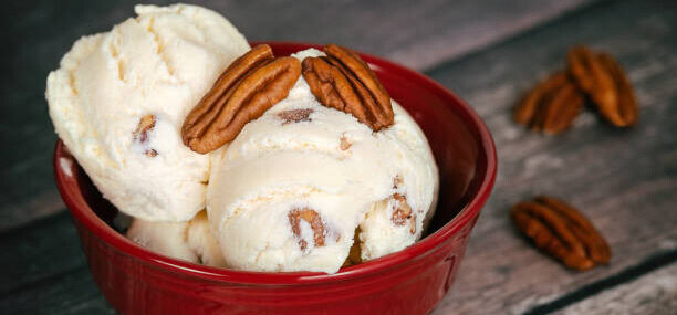 easy-homemade-brown-butter-pecan-ice-cream-image-1-red-bowl-filled-with-pecan-ice-cream-and-fresh-pecans-scattered-frosted-fusions