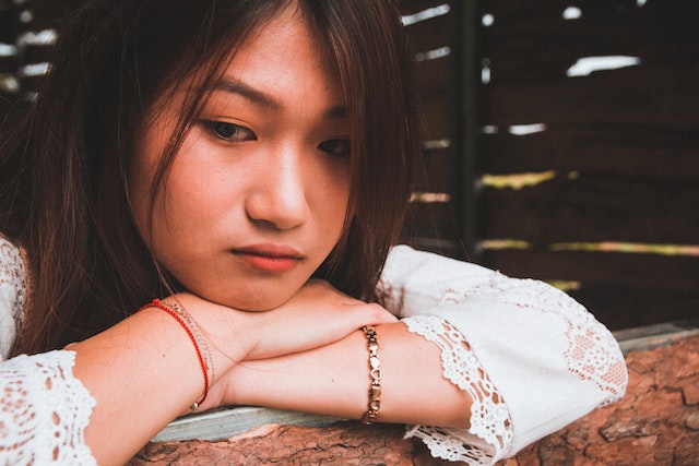 asian-woman-resting-head-on-hands-who-looks-sad