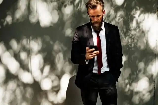 Man in suit using smartphone outdoors