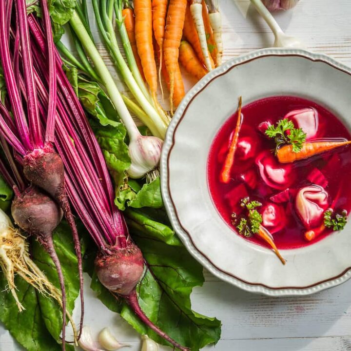 A bowl of Barszczyk soup with carrots and other vegetables.