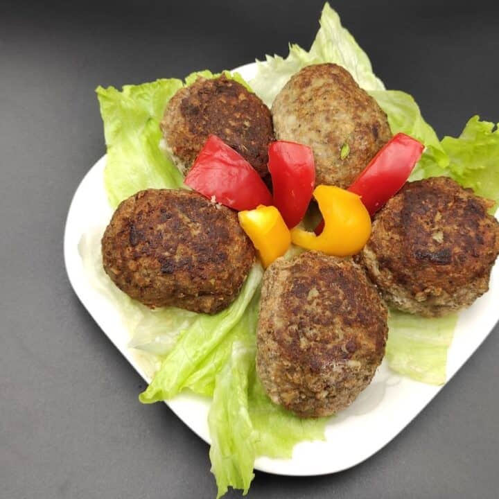 Polish Meatballs on a plate with lettuce and peppers.