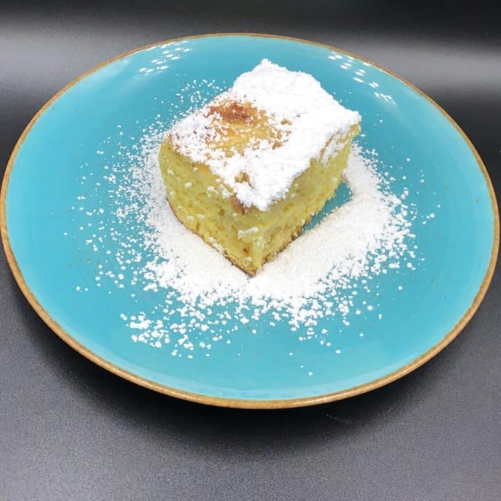 A fluffy sponge cake with powdered sugar on a blue plate.