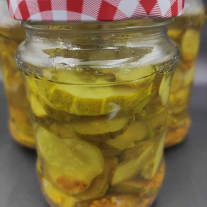 Three jars of pickled cucumbers, also known as canned cucumber salad, are neatly arranged on a table.