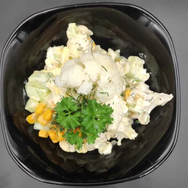 A Polish-inspired black bowl with cauliflower, corn and parsley.