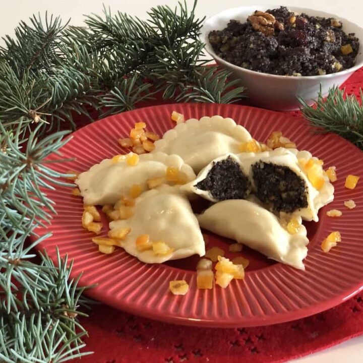 A plate with Polish Poppy Seed Pierogi and a bowl of fruit.