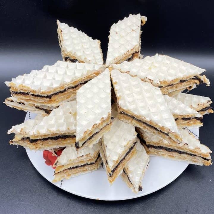 A plate topped with a stack of white pastries, including andrut.
