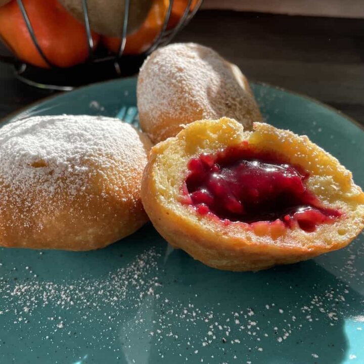 Two Kuyavian donuts with jam on a plate.