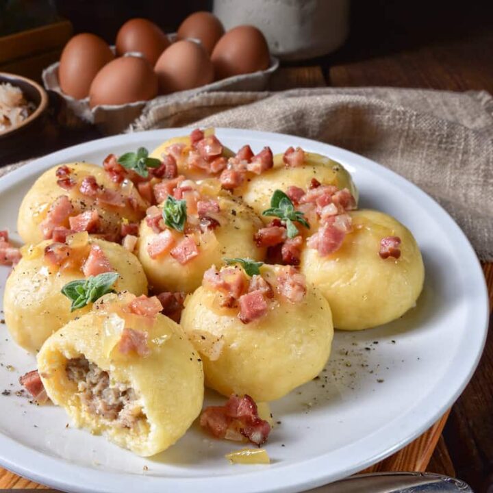 Fried dumplings with bacon, eggs, and pyzy z miesem on a plate.
