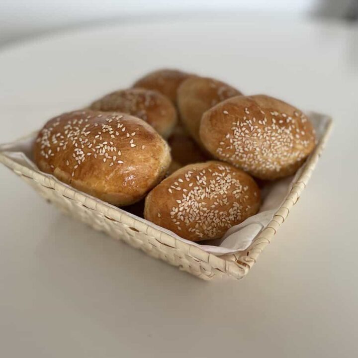 Polish hot dog buns with sesame seeds in a basket on a table.