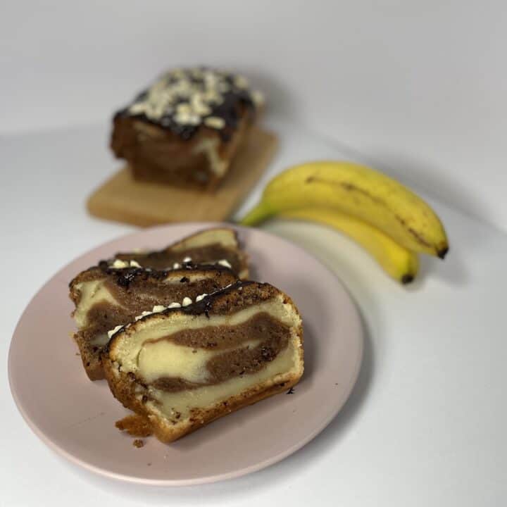 A slice of vegan banana bread on a plate next to a banana.