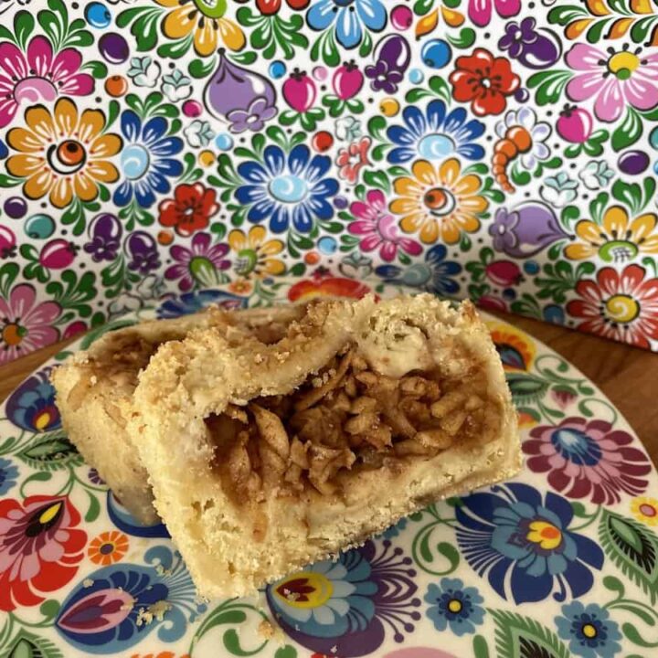 An apple cinnamon babka is sitting on a plate in front of a floral pattern.