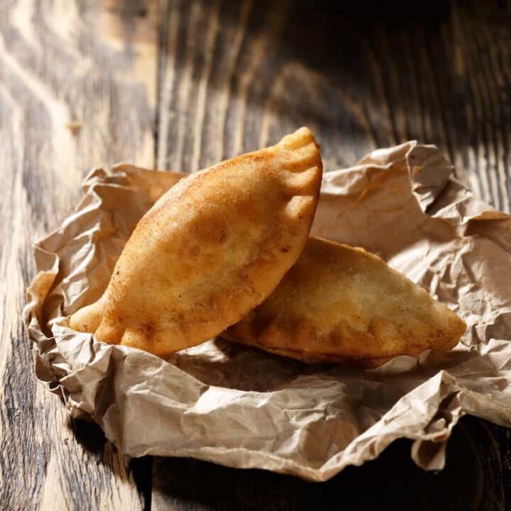 Two golden-brown Polish empanadas on parchment paper.