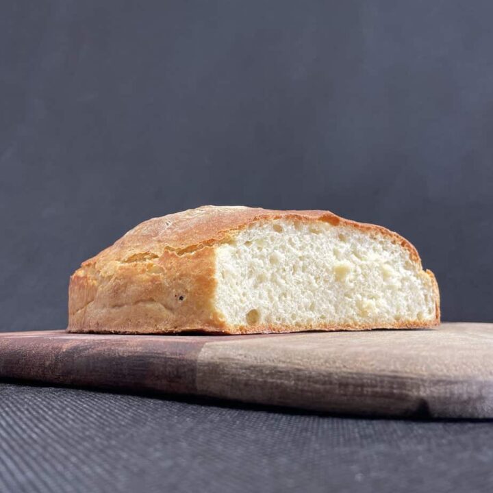 Freshly baked Polish potato bread loaf on a wooden board with a dark background.