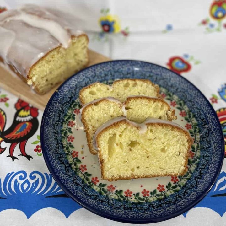 Polish cheese babka with icing, sliced and served on a decorative plate.