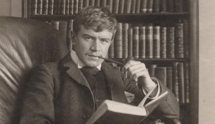 a man sitting in a chair with a book and pen in his mouth