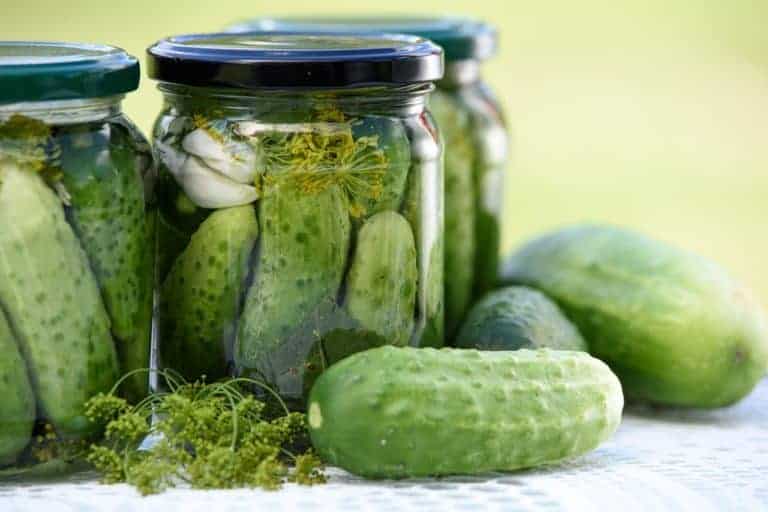 Three jars of pickles, representing a classic Polish dish, sit atop a table.