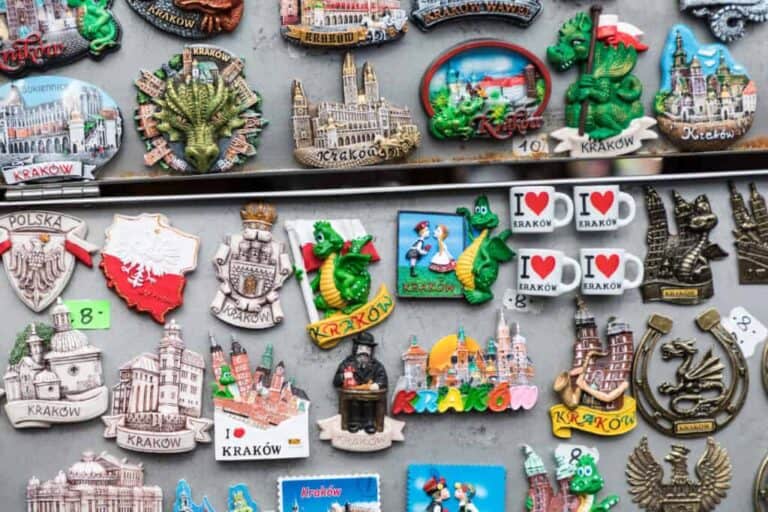 A collection of colorful Krakow-themed magnets featuring landmarks, dragons, cityscapes, and &ldquo;I love Krakow&rdquo; designs displayed on a metal surface&mdash;perfect Polish souvenirs and unique things to buy in Poland.