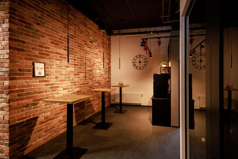 Industrialne wnętrze Centrum Szkoleniowego NT Group z ceglaną ścianą i kameralnym miejscem kawowym