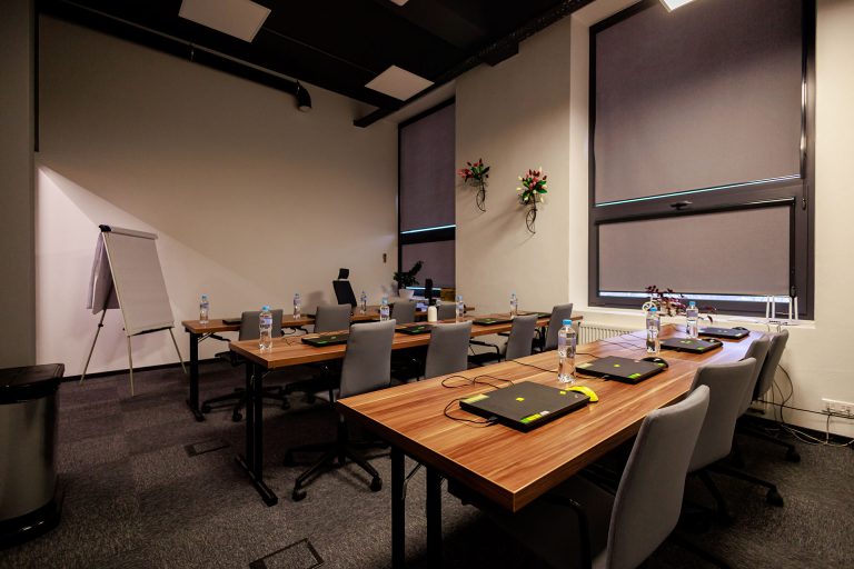 Przestronna sala szkoleniowa NT Group z rozstawionymi stołami i flipchartem