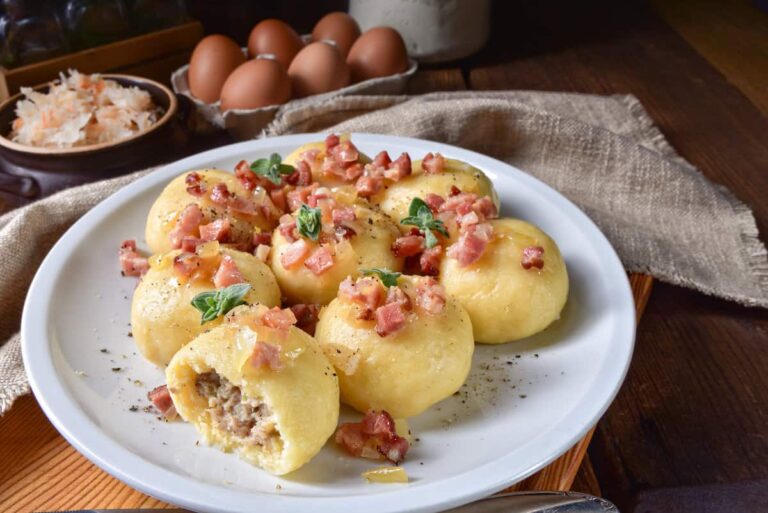 Fried dumplings with bacon, eggs, and pyzy z miesem on a plate.