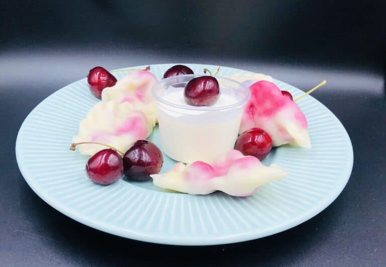 Cherry pierogi, sour cream and cherries in a blue plate.