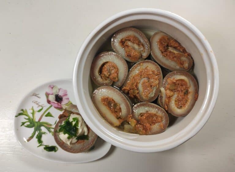 A bowl of stuffed clams and Polish herring rolls on a white plate.