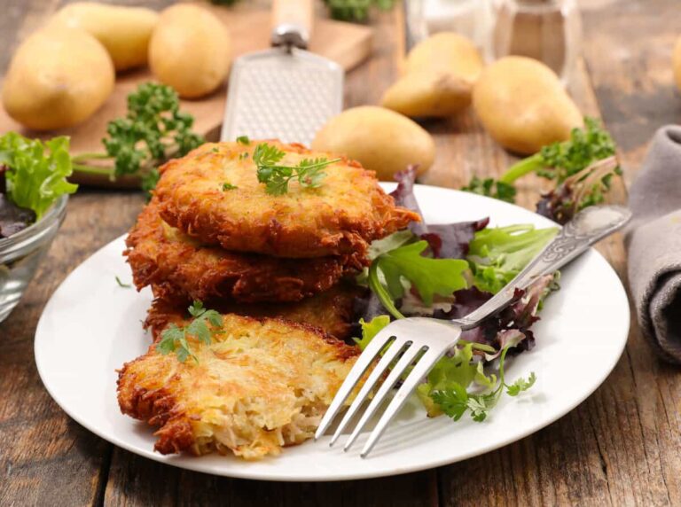 Polish potato pancakes served with a side of green salad on a wooden table.