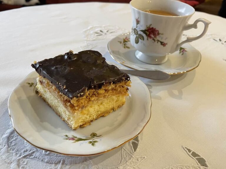 A delicious krolewiec Polish cake recipe on a plate with a cup of coffee.