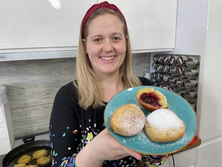 A woman is holding a plate with two donuts on it.