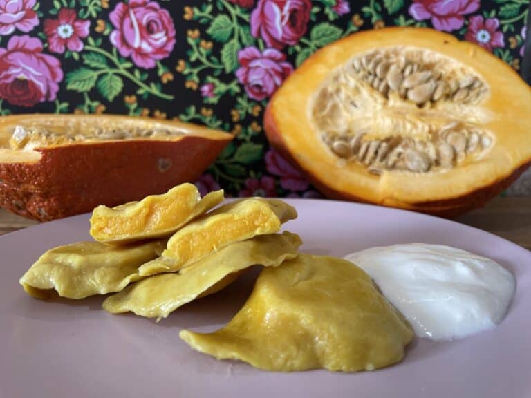 Pumpkin pierogi with sour cream on a plate.