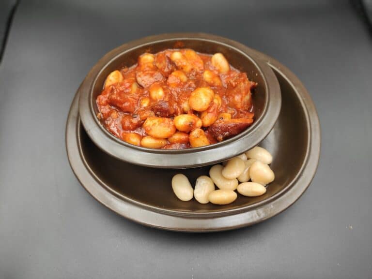 A bowl of Polish beans on a black surface.