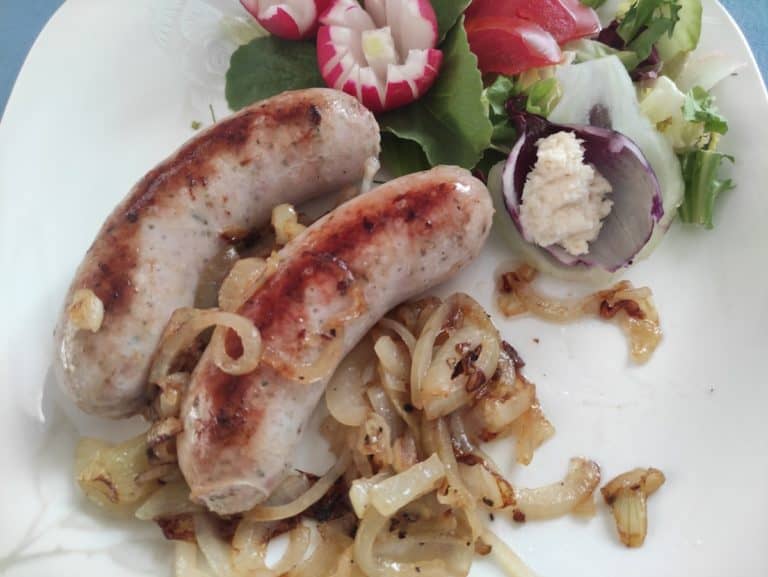 Authentic polish sausages and caramelized onions served on a plate, representing the exquisite flavors of Polish cuisine.