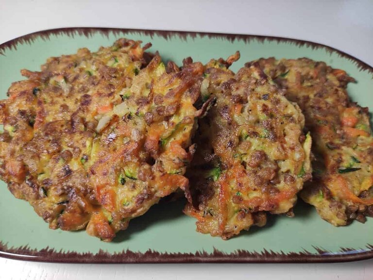 Placki z kaszy gryczanej served with zucchini fritters on a plate.