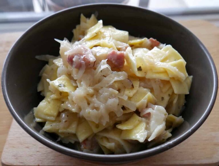 A traditional Polish lazanki recipe featuring a bowl of sauerkraut and ham beautifully presented on a wooden cutting board.