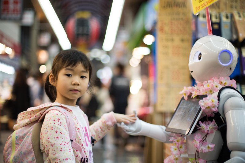 foto de niña apoyando mano izquierda sobre robot digital blanco