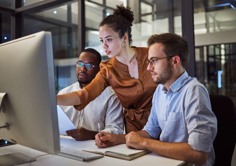 Learning, computer and training business interns in night office with manager, boss and leadership help. Men with technology planning ideas, kpi strategy and marketing innovation vision with mentor.