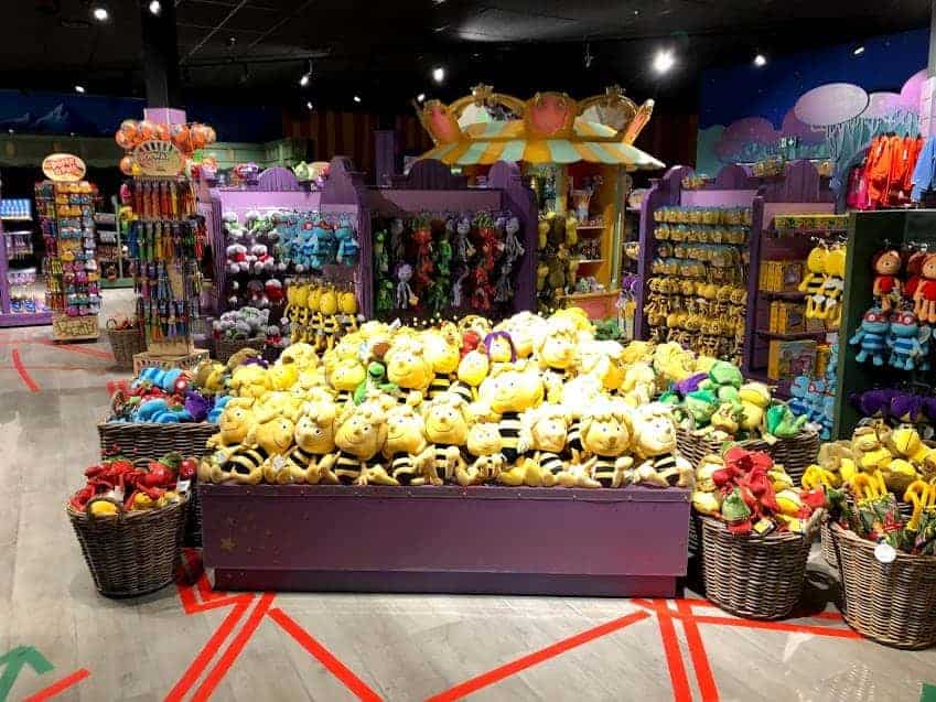 A toy store display at Majaland Amusement Park in Kownaty features shelves and baskets brimming with colorful plush toys, with cheerful yellow bee stuffed animals showcased at the center.